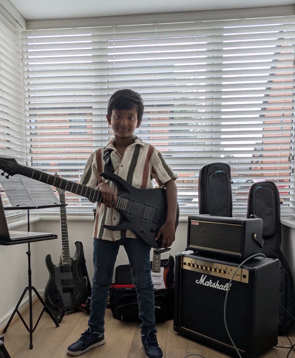 Adrian Abraham standing with his Solar guitar beside a Marshall amplifier at home
