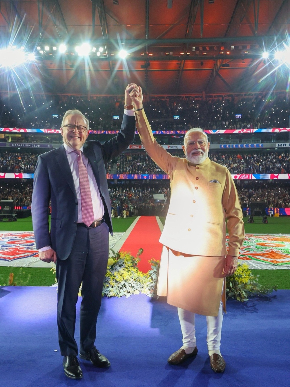 Narendra Modi and Anthony Albanese raise clasped hands on stage