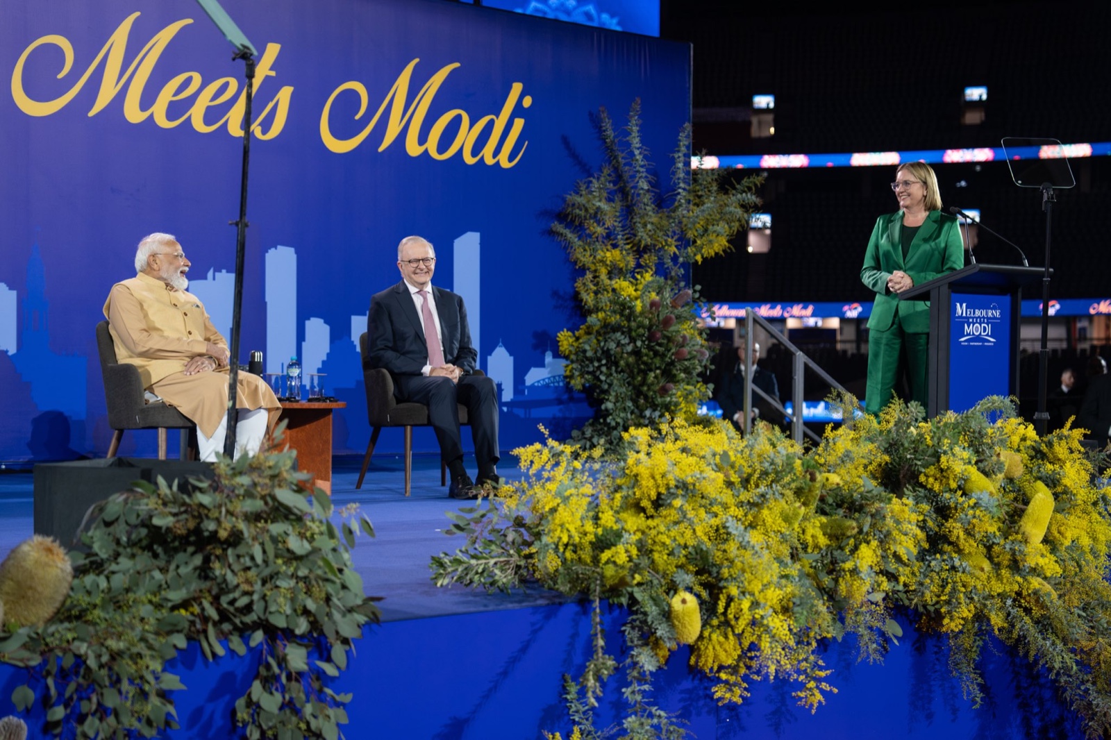 Narendra Modi and Anthony Albanese seated on stage under the Melbourne Meets Modi backdrop